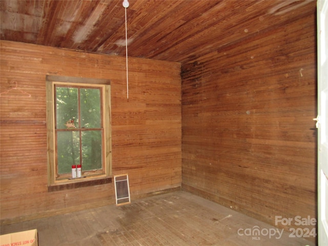 spare room featuring wood ceiling and wooden walls