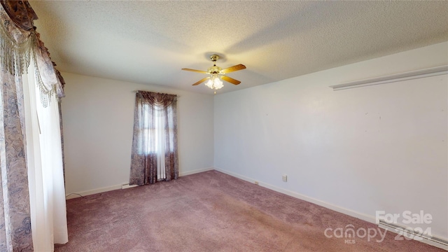 carpeted spare room featuring a textured ceiling and ceiling fan