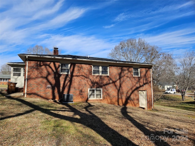 rear view of property with central air condition unit and a yard