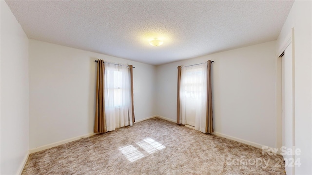 spare room with a textured ceiling and light colored carpet