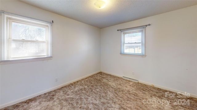 carpeted empty room featuring a textured ceiling and baseboard heating