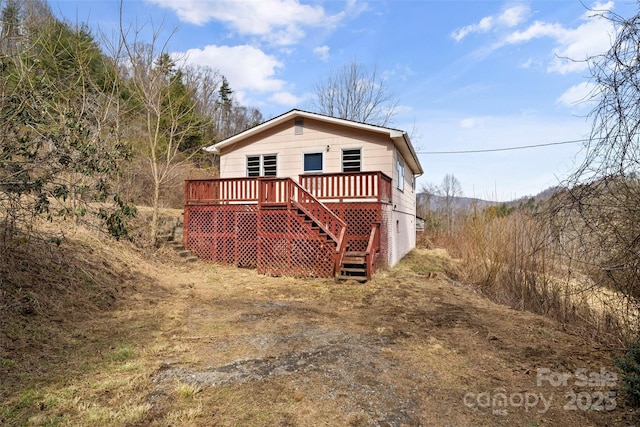 rear view of house featuring stairway and a wooden deck
