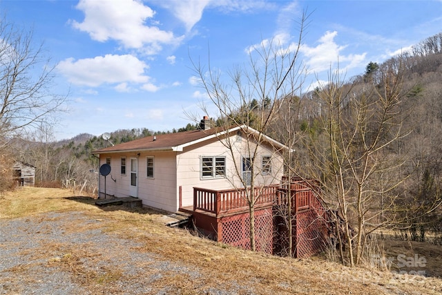 view of side of home with a chimney and a wooden deck