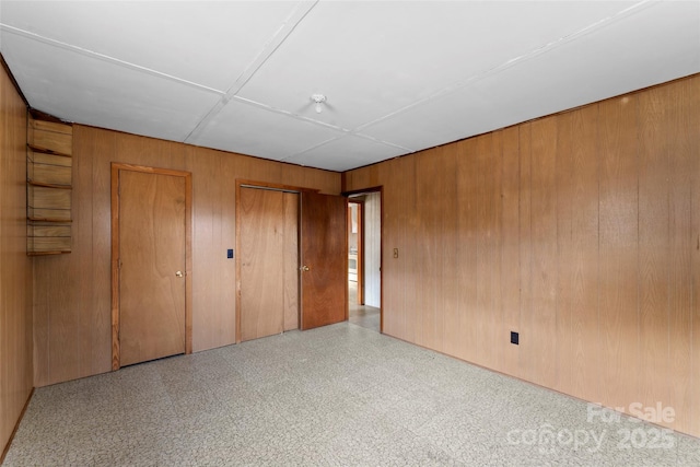 unfurnished bedroom featuring wooden walls and multiple closets