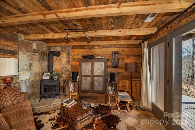 living room featuring a wood stove, wood ceiling, and beam ceiling