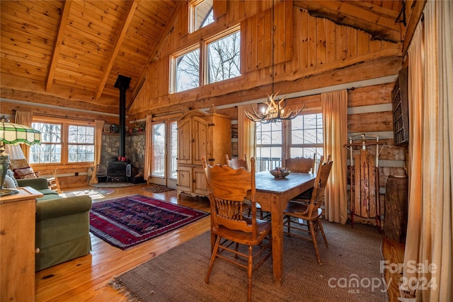 dining space featuring a wood stove, wood ceiling, a chandelier, wood-type flooring, and high vaulted ceiling