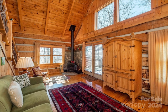 living room featuring a wood stove, light hardwood / wood-style flooring, wood ceiling, and wooden walls