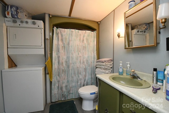 bathroom featuring toilet, stacked washer / dryer, and vanity