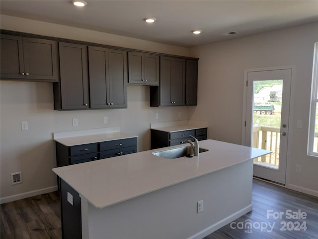 kitchen with a center island with sink, sink, and dark wood-type flooring