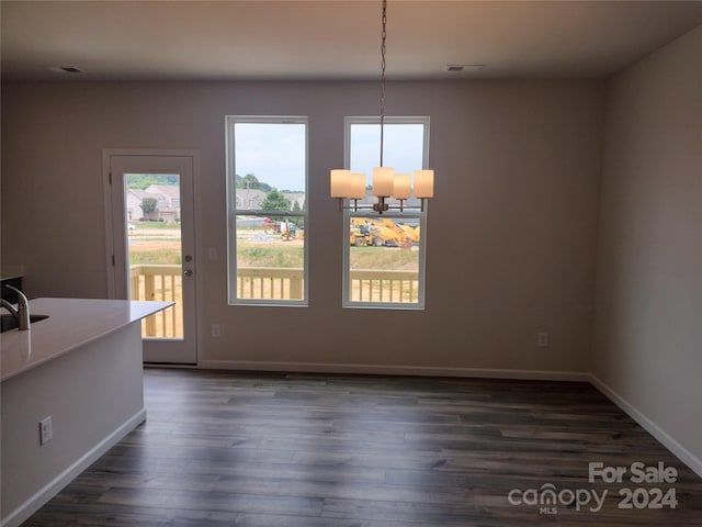 unfurnished dining area featuring a chandelier and dark hardwood / wood-style floors