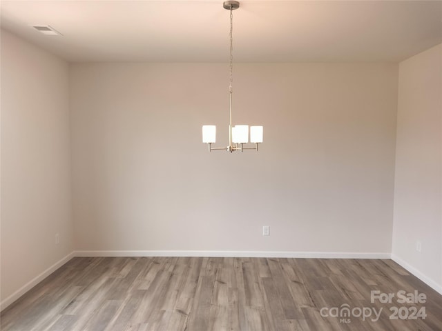 spare room featuring hardwood / wood-style flooring and a chandelier