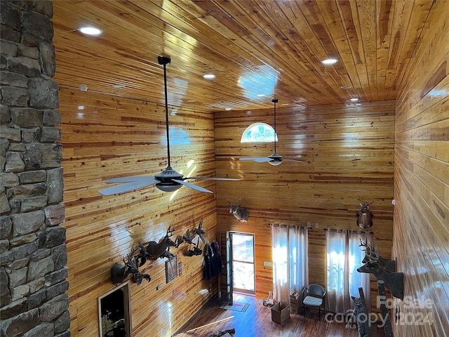 interior space featuring wood walls, wood ceiling, dark hardwood / wood-style floors, and ceiling fan