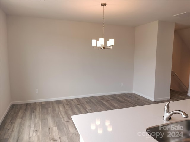 kitchen with wood-type flooring, an inviting chandelier, and hanging light fixtures