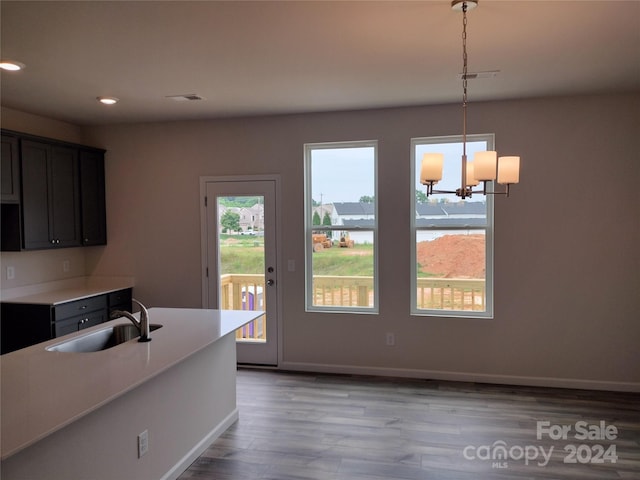 kitchen with pendant lighting, light wood-type flooring, sink, and an inviting chandelier