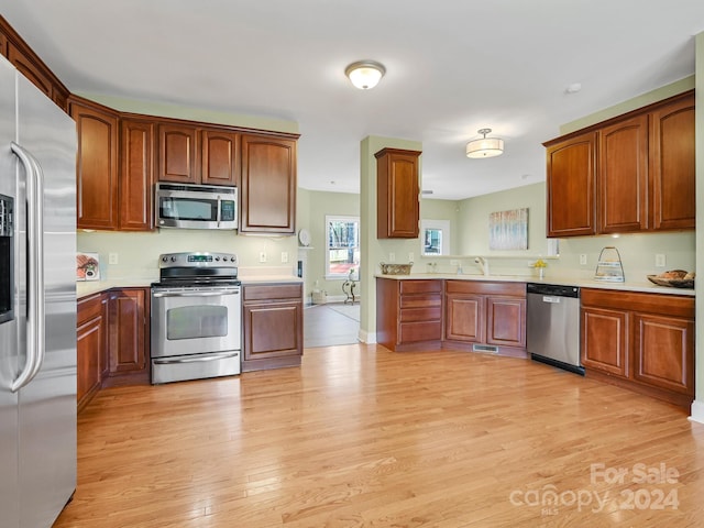 kitchen featuring appliances with stainless steel finishes, sink, and light hardwood / wood-style flooring