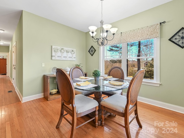 dining area featuring light wood-type flooring and a notable chandelier