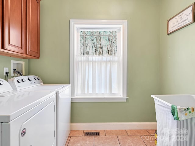 clothes washing area featuring washing machine and dryer, light tile patterned flooring, and cabinets