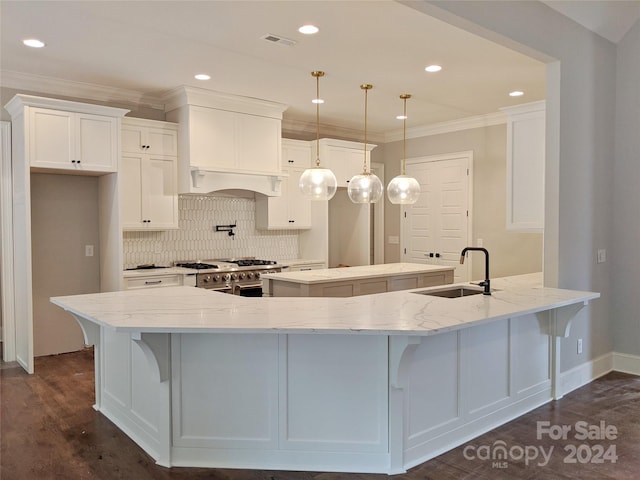 kitchen with hanging light fixtures, dark wood-type flooring, sink, white cabinetry, and range with two ovens