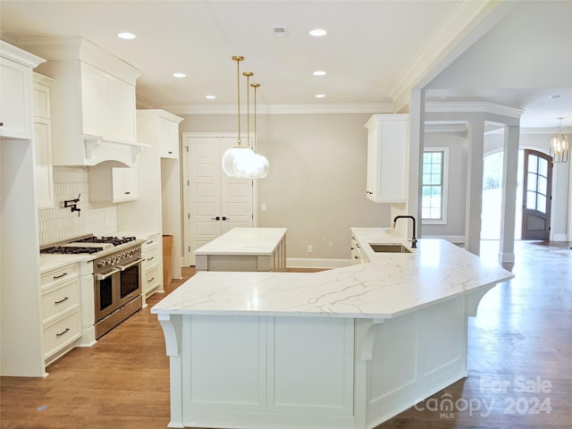 kitchen with white cabinetry, double oven range, hanging light fixtures, and light hardwood / wood-style flooring