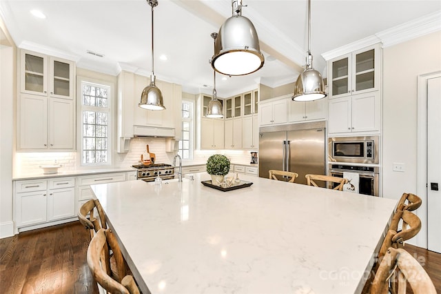 kitchen with backsplash, a kitchen bar, built in appliances, and pendant lighting