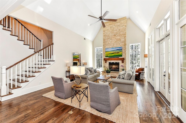 living room with high vaulted ceiling, ceiling fan, french doors, a stone fireplace, and dark hardwood / wood-style floors