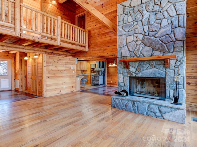 unfurnished living room featuring wooden walls, wood-type flooring, high vaulted ceiling, wooden ceiling, and a fireplace