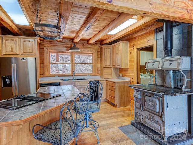 kitchen with stainless steel fridge, light brown cabinetry, wood ceiling, sink, and wood walls