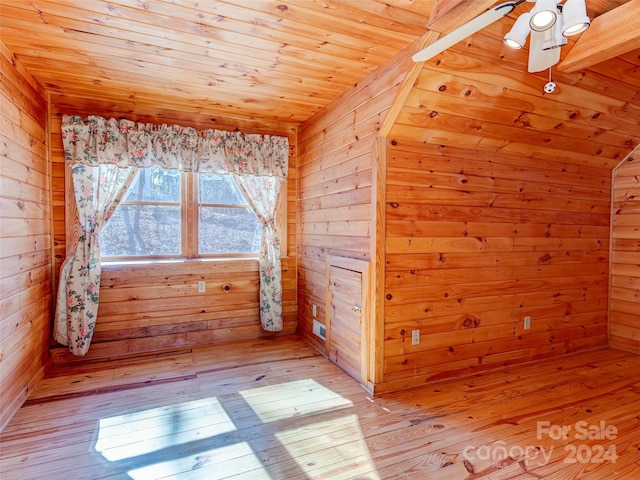 empty room with ceiling fan, light hardwood / wood-style floors, lofted ceiling, wooden walls, and wood ceiling