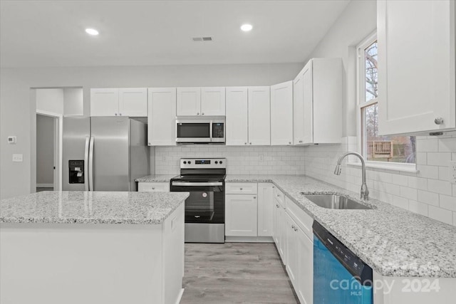 kitchen with appliances with stainless steel finishes, light stone counters, white cabinets, light hardwood / wood-style flooring, and sink