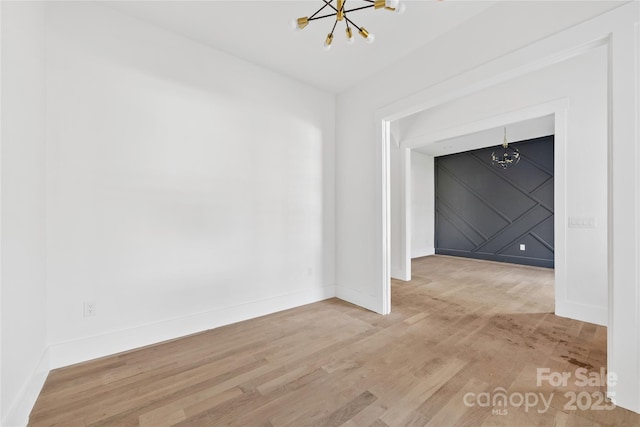 unfurnished room featuring a chandelier and light hardwood / wood-style floors