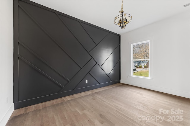 unfurnished room featuring a notable chandelier and light hardwood / wood-style floors