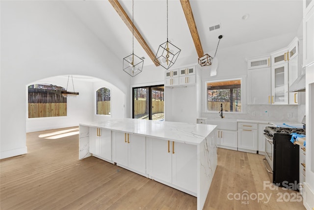 kitchen featuring sink, hanging light fixtures, stainless steel range with gas cooktop, a kitchen island, and white cabinets