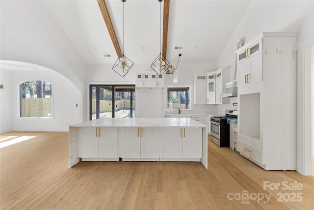 kitchen featuring a kitchen island, white cabinetry, hanging light fixtures, light hardwood / wood-style floors, and stainless steel gas range