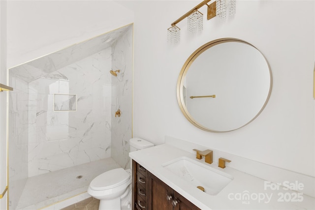 bathroom featuring vanity, a tile shower, and toilet