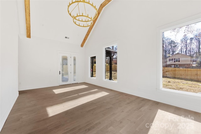 interior space with dark wood-type flooring, a wealth of natural light, a notable chandelier, and high vaulted ceiling