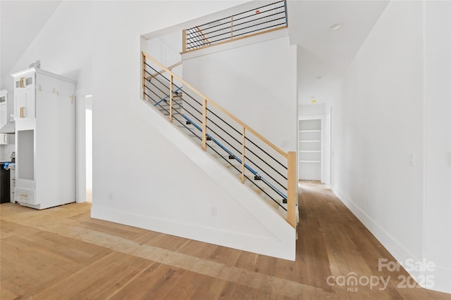 staircase with hardwood / wood-style floors and a high ceiling