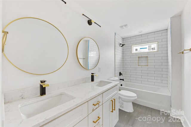 full bathroom featuring vanity, hardwood / wood-style flooring, toilet, and tiled shower / bath