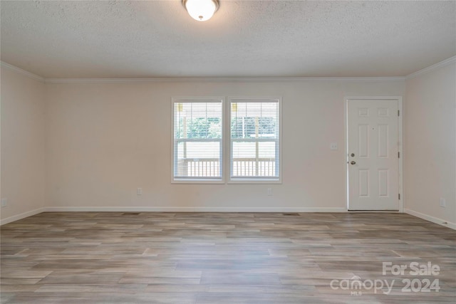 unfurnished room featuring a textured ceiling, ornamental molding, and light hardwood / wood-style floors