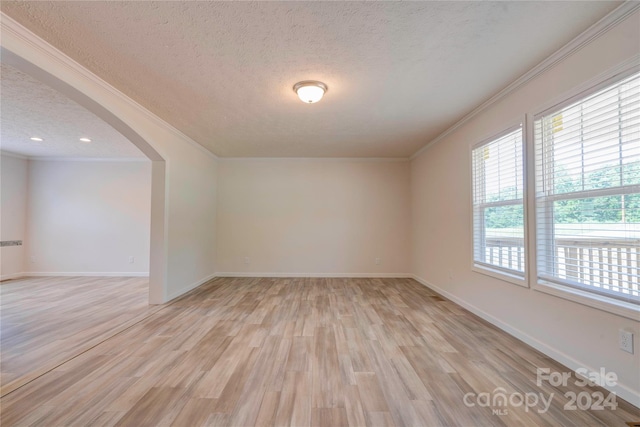 spare room featuring light wood-type flooring, crown molding, and a textured ceiling