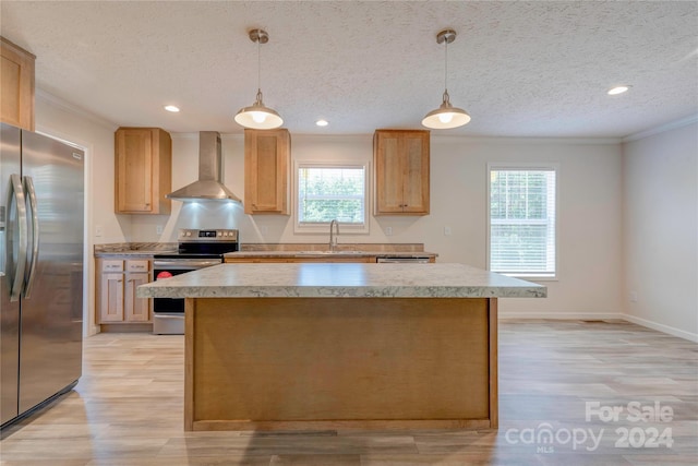 kitchen with hanging light fixtures, appliances with stainless steel finishes, wall chimney exhaust hood, and a textured ceiling