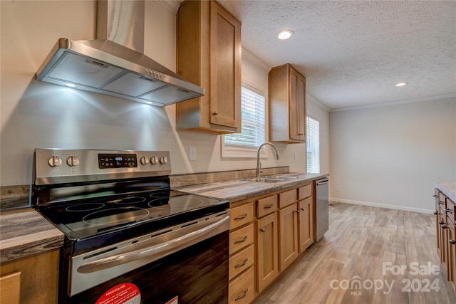 kitchen with appliances with stainless steel finishes, wall chimney exhaust hood, a textured ceiling, crown molding, and sink