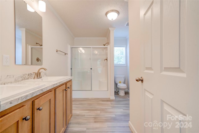 bathroom featuring hardwood / wood-style floors, a textured ceiling, an enclosed shower, toilet, and crown molding