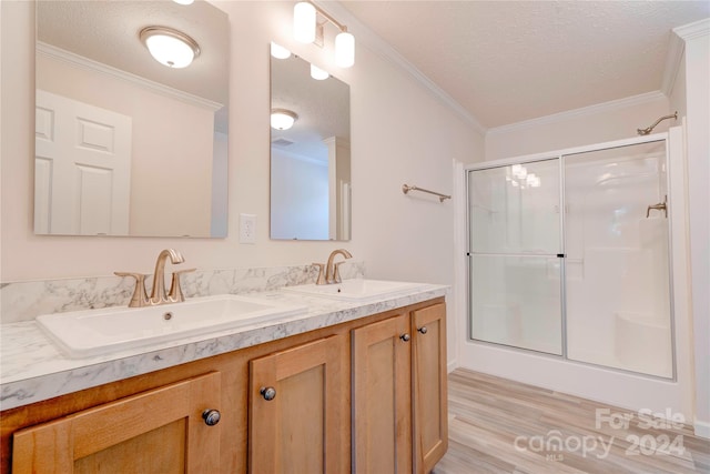 bathroom featuring vanity, a shower with door, crown molding, and a textured ceiling