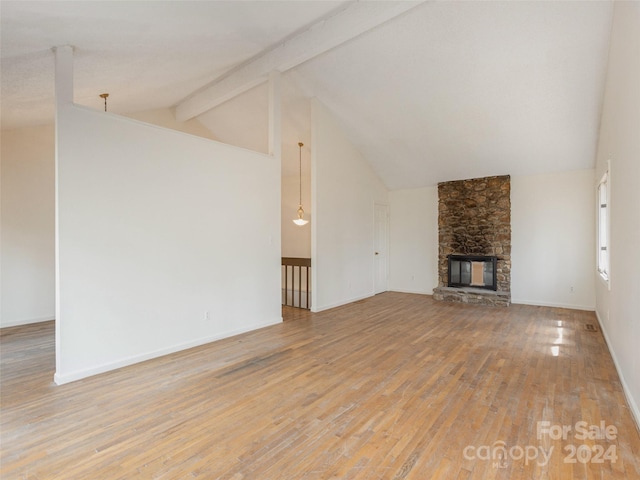 unfurnished living room with high vaulted ceiling, beam ceiling, light hardwood / wood-style floors, and a stone fireplace