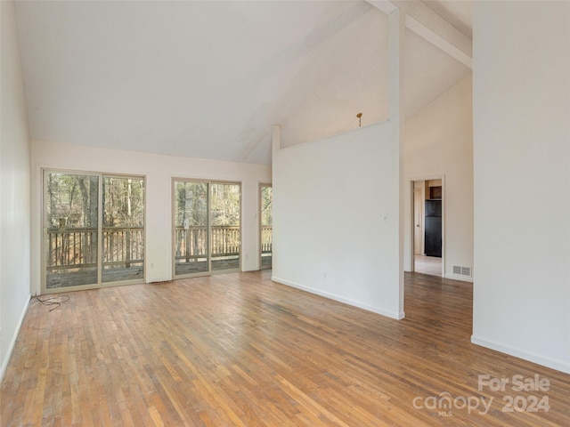 empty room featuring high vaulted ceiling and hardwood / wood-style flooring