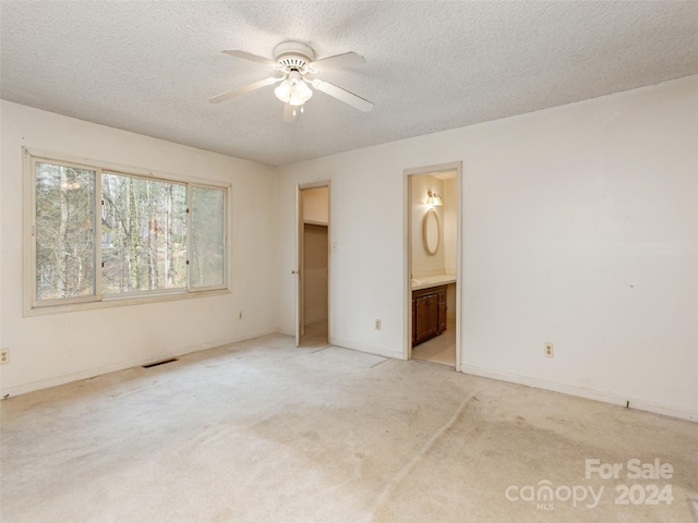 spare room with light carpet, ceiling fan, and a textured ceiling