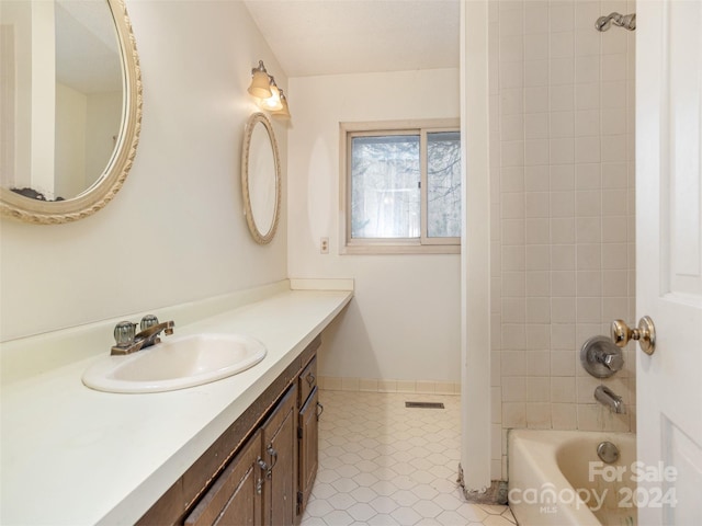 bathroom with vanity with extensive cabinet space, tile flooring, and tiled shower / bath combo