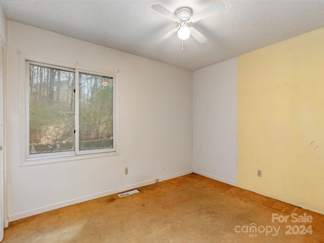 empty room with a textured ceiling, light colored carpet, and ceiling fan