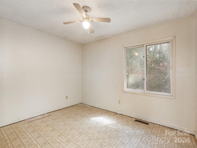 spare room with light tile flooring, ceiling fan, and a textured ceiling