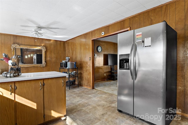 kitchen with ceiling fan, wooden walls, and stainless steel fridge with ice dispenser